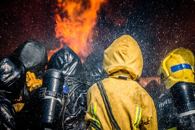 rear view of firefighters spraying water on fire
