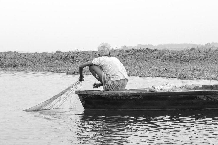 Photo rear view of fisherman crouching on fishing boat in lake against sky