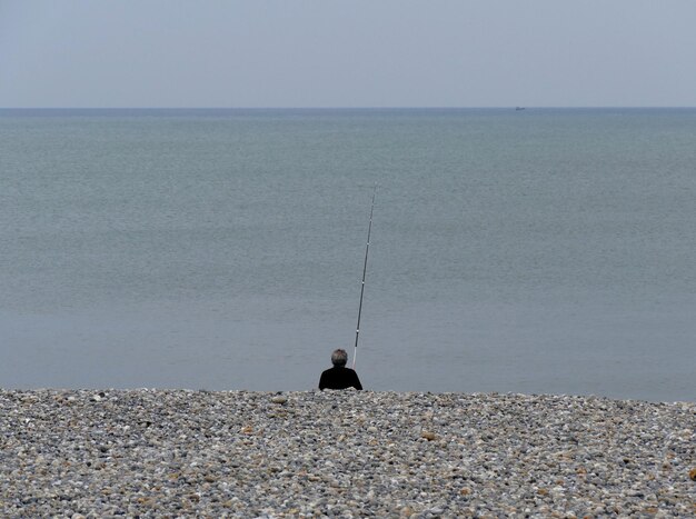 空の背景に海から釣りをしている漁師の後ろの景色