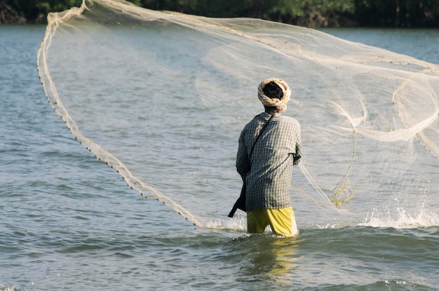 Foto vista posteriore di un pescatore che getta la rete nel lago