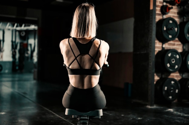 Rear view of a fit woman doing cardio exercises on a machine in a gym