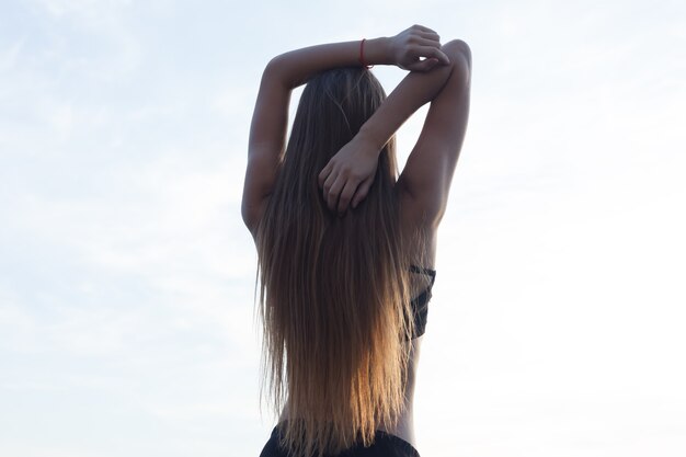 Foto vista posteriore della giovane donna adatta che allunga le braccia all'aperto