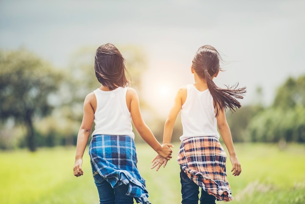 Rear view of friends holding hands while standing on grassy field