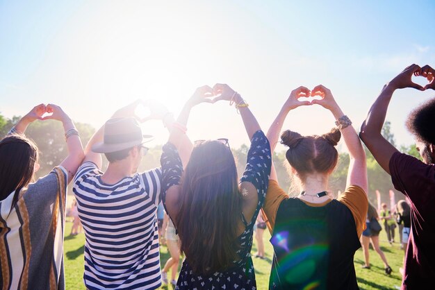 Foto vista posteriore di amici che fanno la forma di un cuore al festival musicale