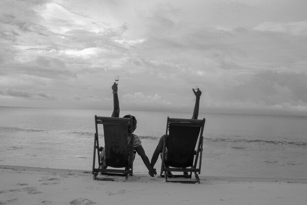 Photo rear view of friends sitting on chair at beach