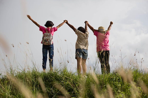 rear view of friends standing on field against sky