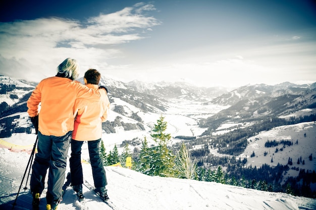 rear view of friends standing on snow covered mountain against sky