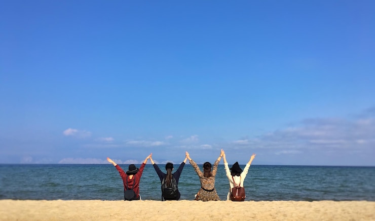 Photo 空に向かってビーチで腕を上げた友達の後ろの景色