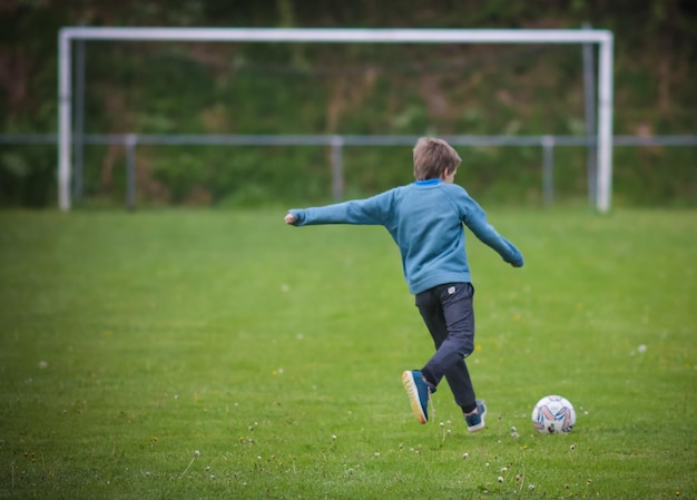 rear view full length of boy playing soccer on field