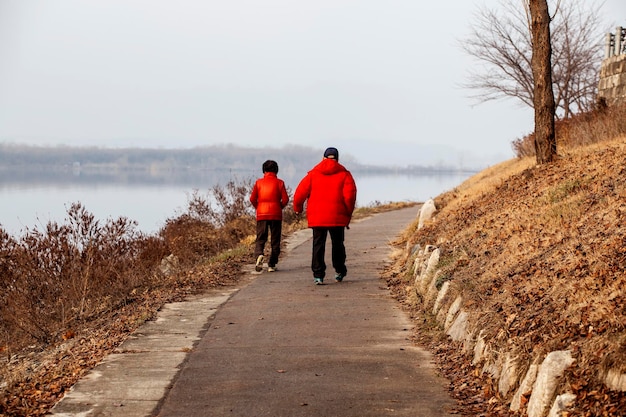 Foto vista posteriore a tutta lunghezza del padre che cammina con il figlio sul lago sul sentiero pedonale