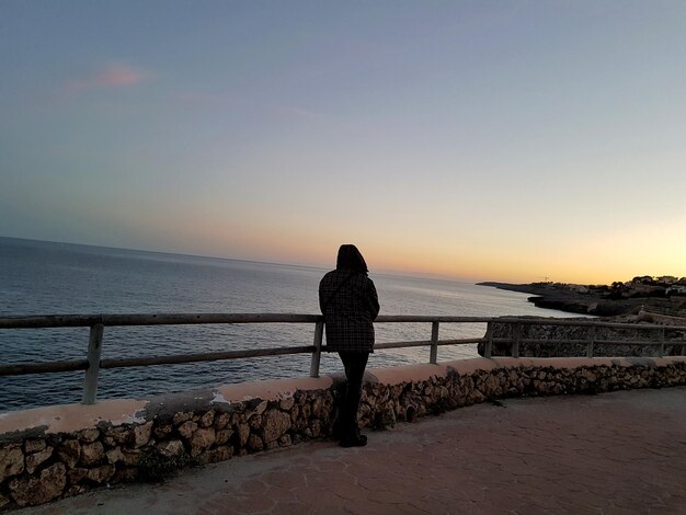 Rear view full length of man at observation point looking at sea during sunset