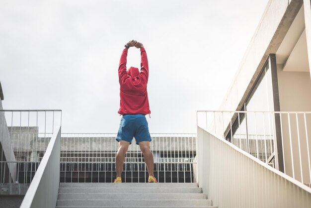 写真 明るい空の向こうの階段で運動している男性の全長の後ろの景色