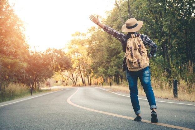 写真 道路でヒッチハイクをしている女性の全長の後ろの景色