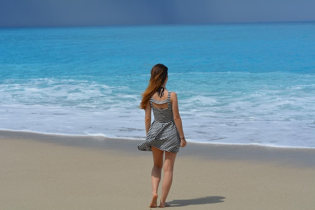 浜辺に立っている女性の全長の後ろの景色