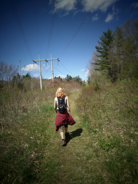 Photo rear view full length of woman walking on grassy field against sky