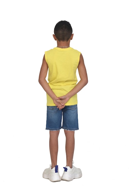 rear view of full portrait of a boy dressed in shorts and sleeveless with hands on back on white background