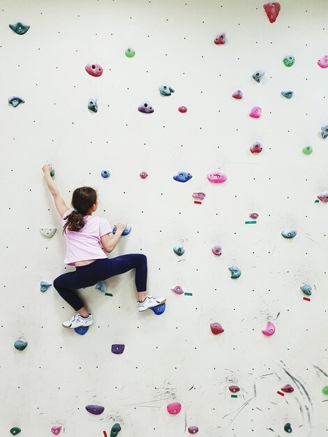 Photo rear view of girl climbing wall