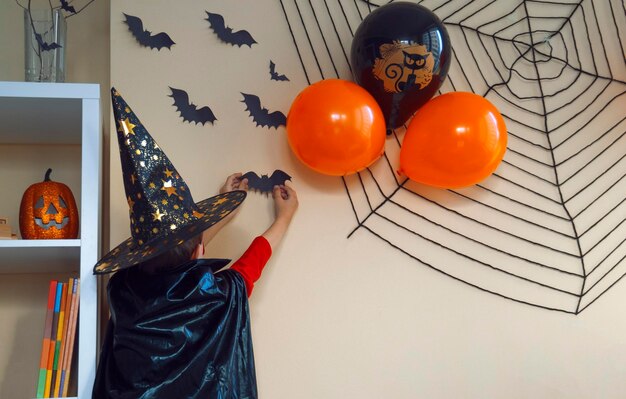 Photo rear view of girl decorating wall during halloween