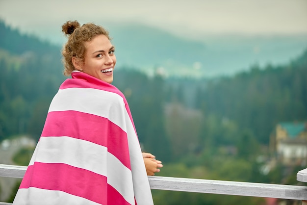 Rear view of girl leaning on railing on terrace of resort.