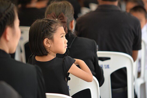 Photo rear view of girl looking away while sitting on chair