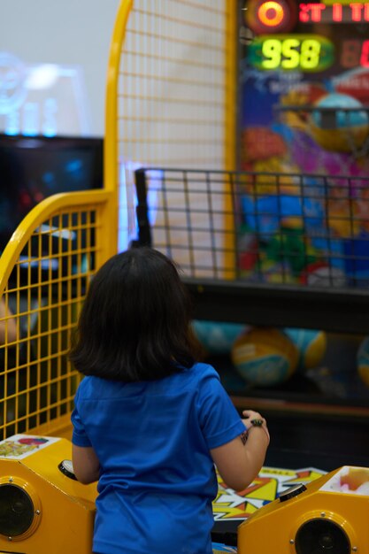 Rear view of a girl play basketball game on game arcade background