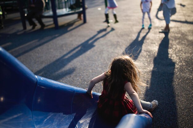 Photo rear view of girl playing on slide