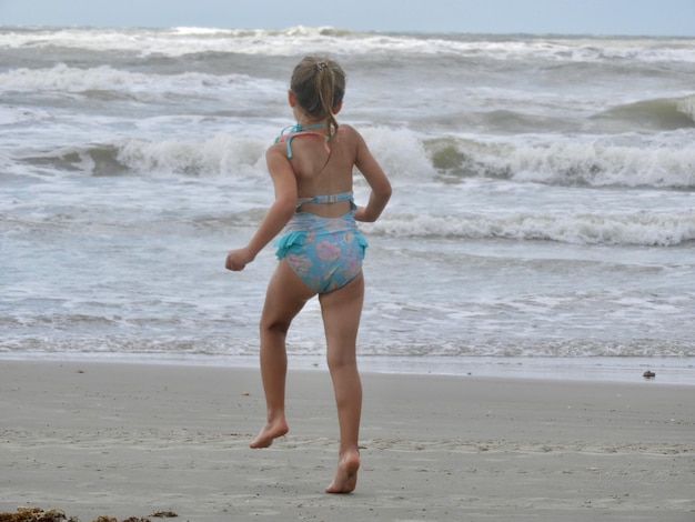 Rear view of girl running at beach