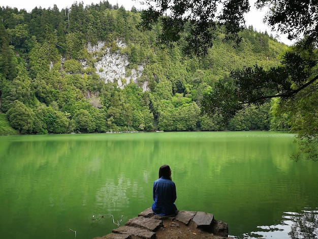 Photo rear view of girl sitting by lake