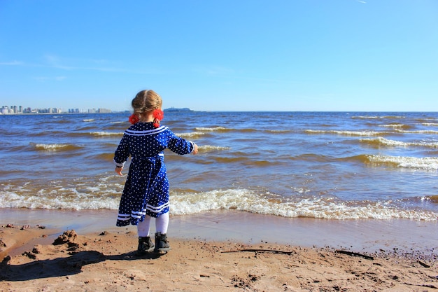 Foto vista posteriore di una ragazza in piedi sulla spiaggia contro il cielo blu durante una giornata di sole