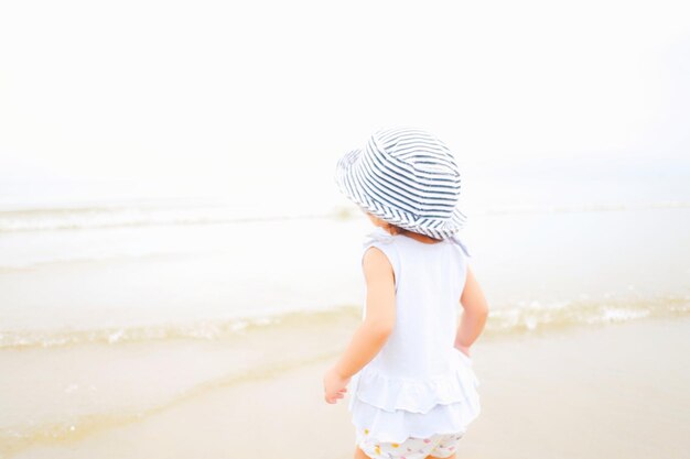 空に向かってビーチに立っている女の子の後ろの景色