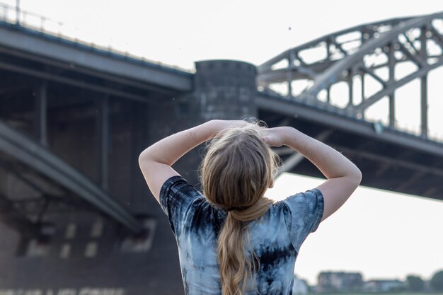 Foto vista posteriore di una ragazza in piedi sul ponte contro un cielo limpido