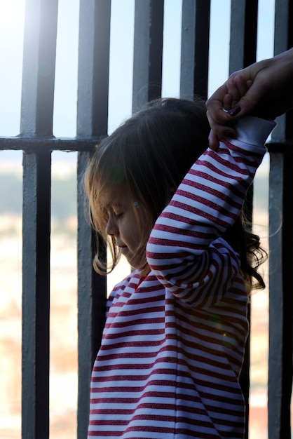 Photo rear view of girl standing by window