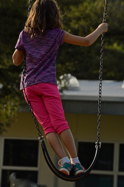 Rear view of girl on swing in playground