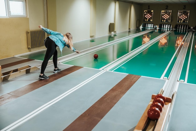 Rear view of a girl throwing the bowling ball.