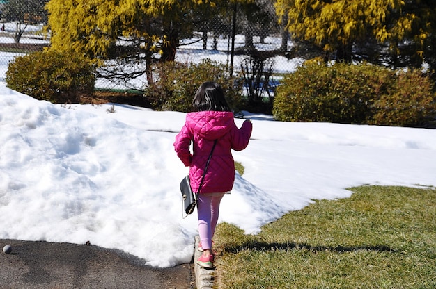 Photo rear view of girl walking by plants during winter