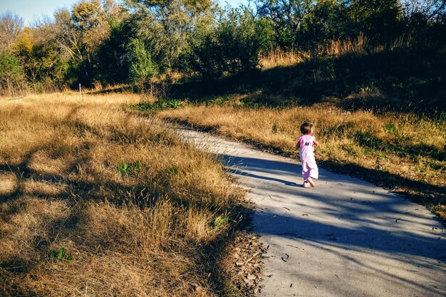 Photo rear view of girl walking on footpath in forest