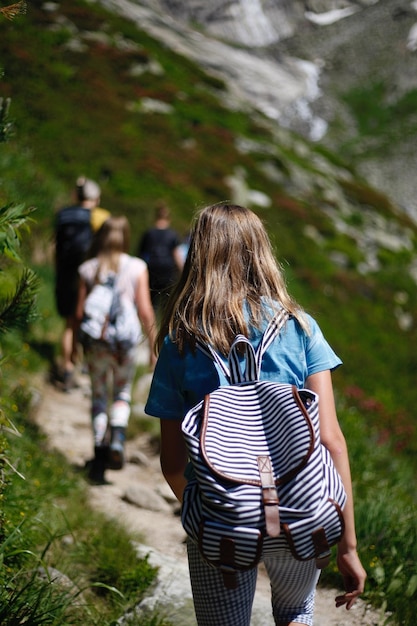 Rear view of girl walking on road amidst field
