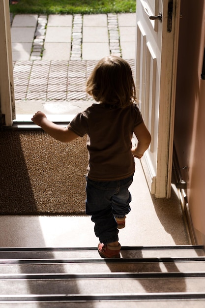 Photo rear view of girl walking on staircase at home