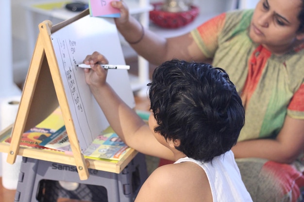 Photo rear view of girl writing on board