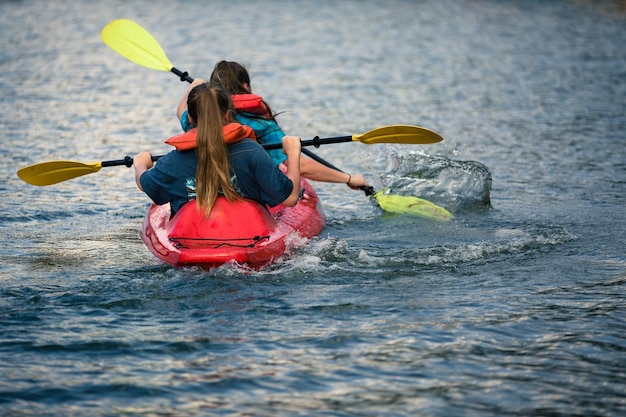 Photo rear view of girls kayaking in sea