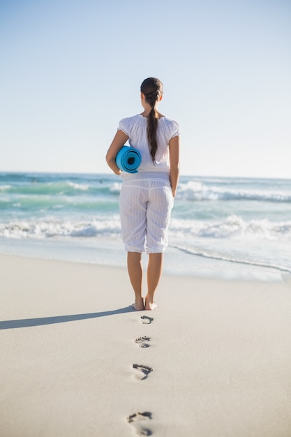 Rear view of gorgeous woman holding exercise mat