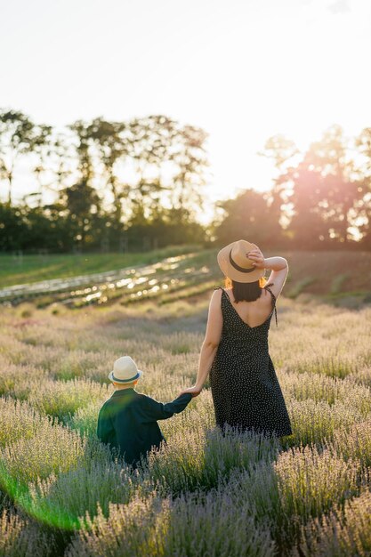 Rear view of happy family of mother and son spending time together in lavender field