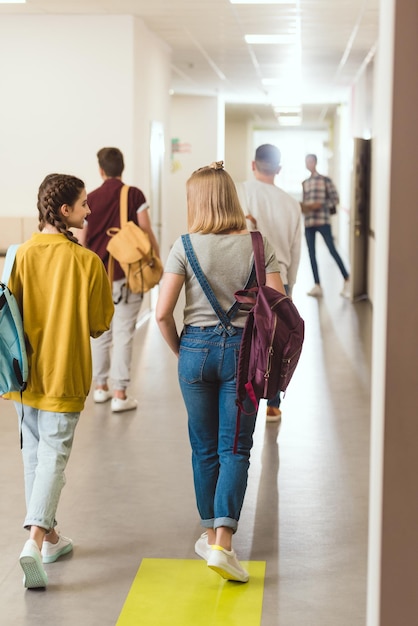 学校の廊下を歩く高校生の後ろの景色