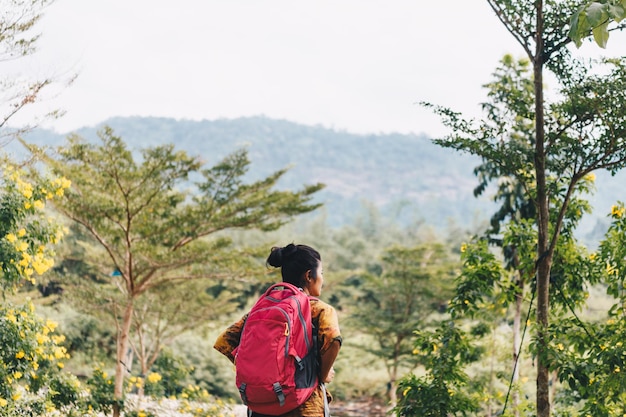 Rear view of hiker with backpack standing on mountain against sky