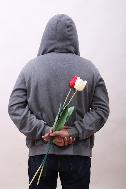 Rear view of hooded man holding flowers