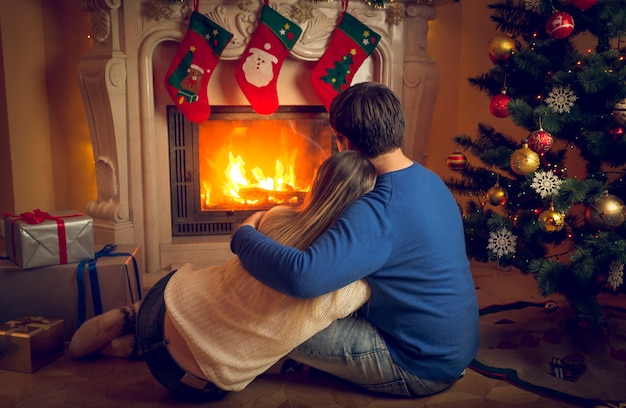 Rear view image of couple relaxing by the fireplace