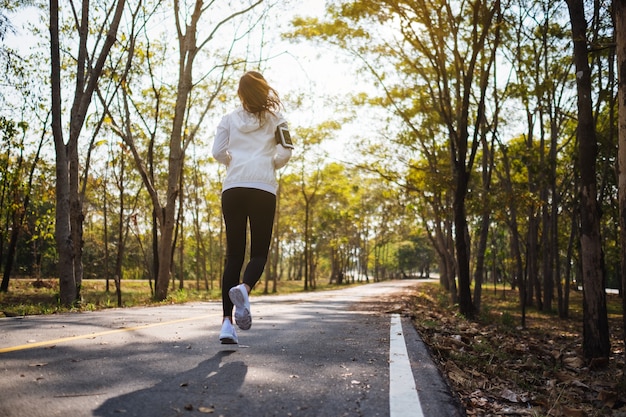 Immagine vista posteriore di una giovane donna asiatica che fa jogging nel parco cittadino al mattino