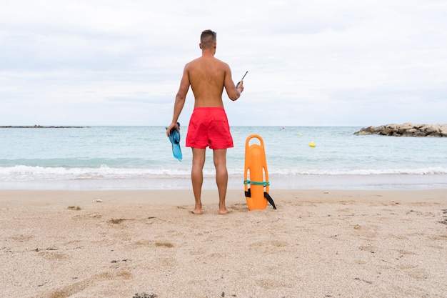 Premium Photo | Rear view of a lifeguard standing on the beach