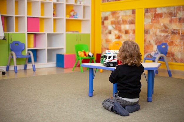 Rear view of a little boy in kindergarten plays alone