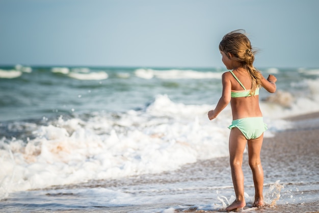 熱帯の国で夏休みの暖かい夏の日に海で泳いでいる小さな4歳の少女の背面図